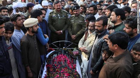 Pessoas estão ao lado do corpo de um homem que, segundo a polícia, foi executado sumariamente por uma multidão, na vila de Tulamba, no centro do Paquistão, em 13 de fevereiro de 2022.