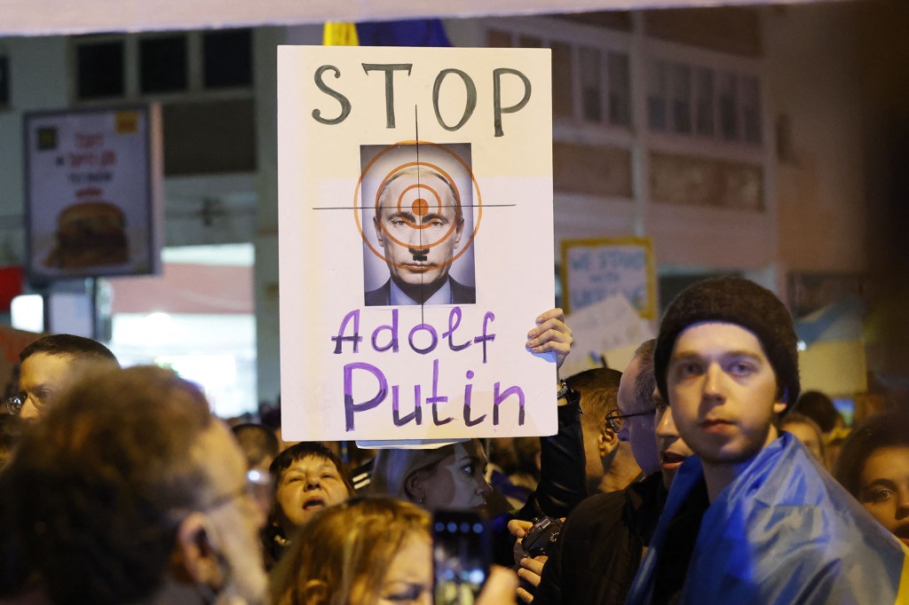 Manifestantes seguram cartazes em frente à Embaixada da Rússia em Tel Aviv protestando contra a invasão. 