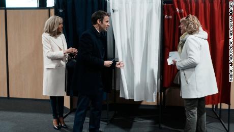 O presidente francês Emmanuel Macron (centro), ao lado de sua esposa Brigitte Macron (esquerda), conversa com um morador antes de votar no primeiro turno da eleição presidencial no domingo.