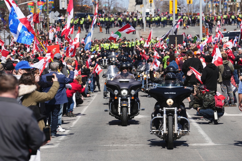 Manifestantes aplaudem enquanto motociclistas passam por uma manifestação, parte de uma manifestação no estilo caravana "trovão rolando"em Ottawa, sábado, 30 de abril de 2022