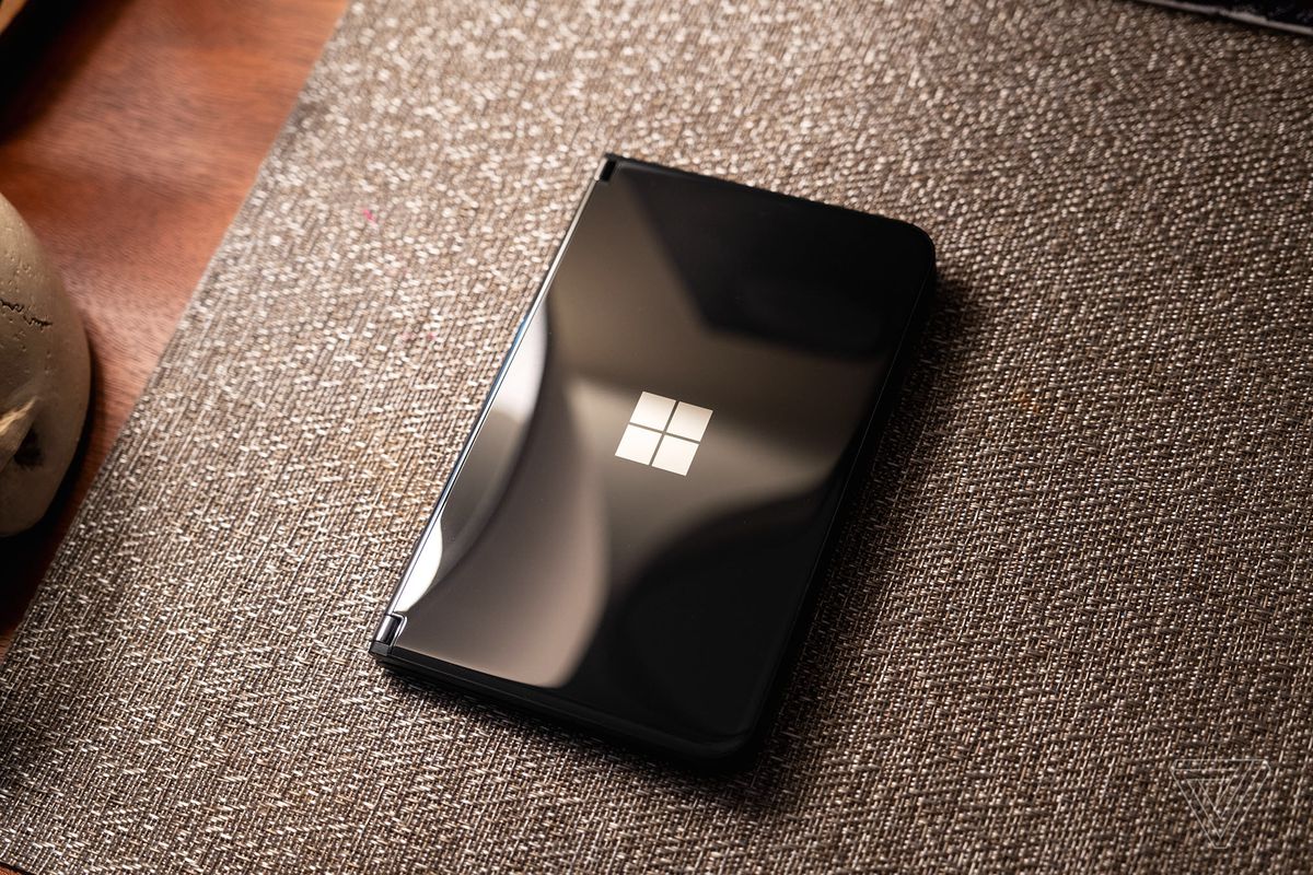 Microsoft Surface Duo 2 preto fechado e sentado em um colchão.